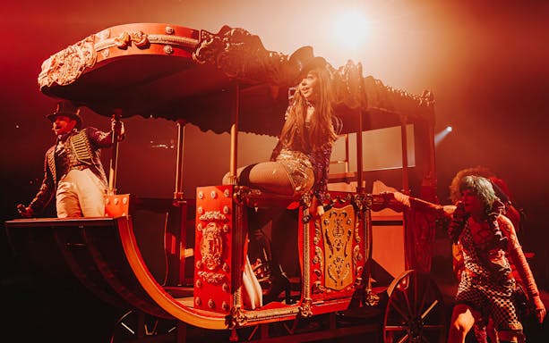 Performer in a vibrant circus carriage during a theatrical show.
