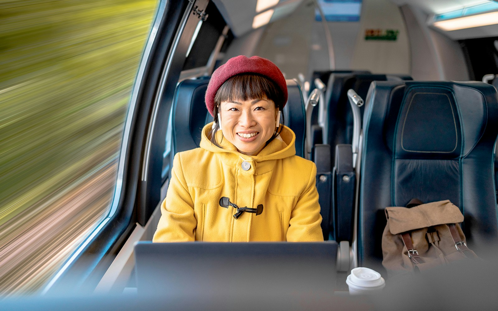 Japanese woman seated in first class on a Bullet train, enjoying scenic views.