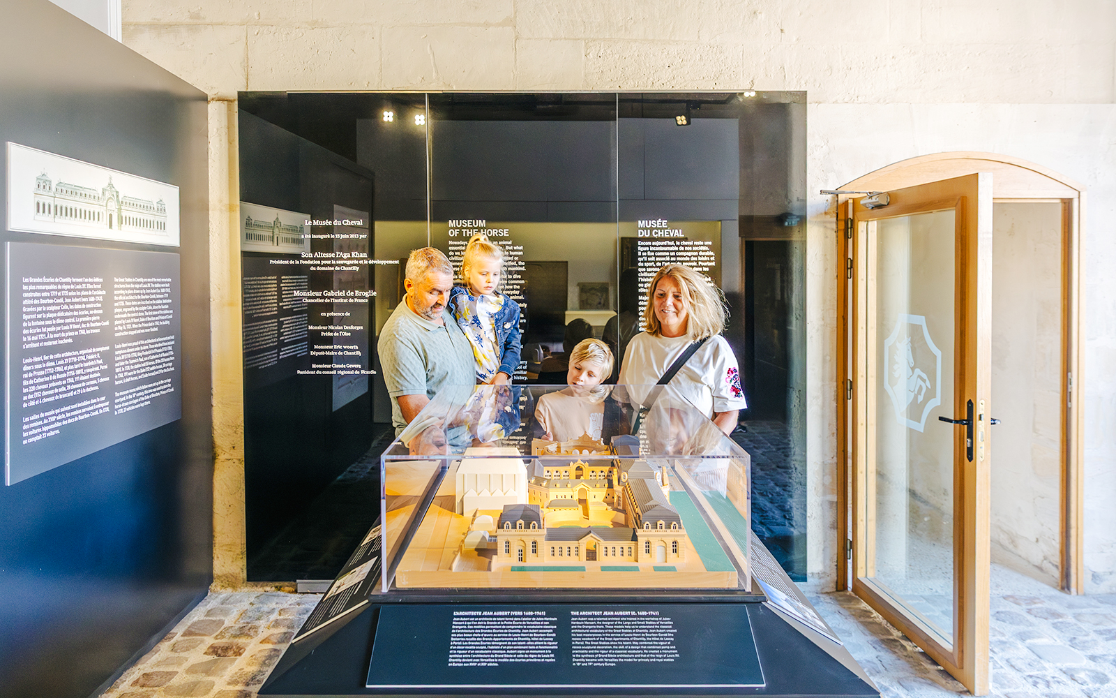 Family observing a model of the Chateau of Chantilly at the museum exhibit.