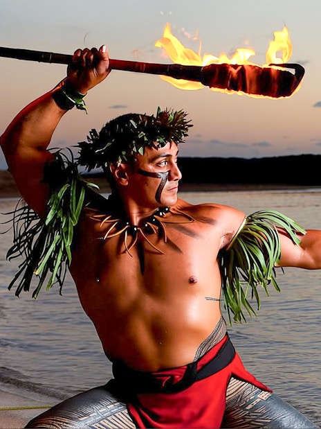 Fire dancer performing at sunset on the beach at Paradise Cove Luau, Hawaii.