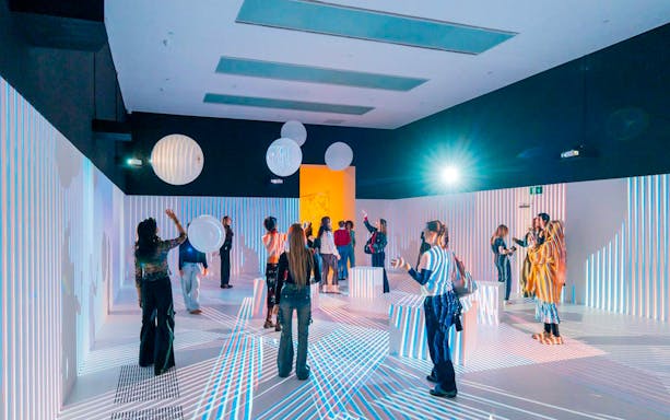 Visitors interacting with light installations at Tate Modern's Electric Dreams exhibition.