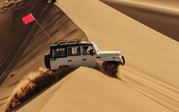 Jeep driving through sand dunes in Hurghada desert adventure.