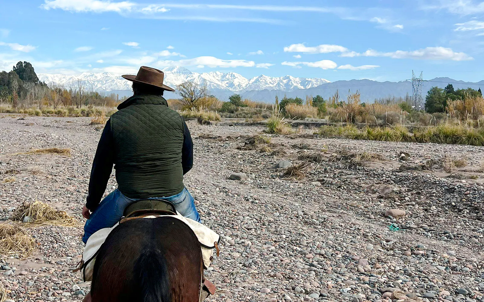 Horseback rider on rocky terrain with Andes mountains in Lunlunta, Argentina.