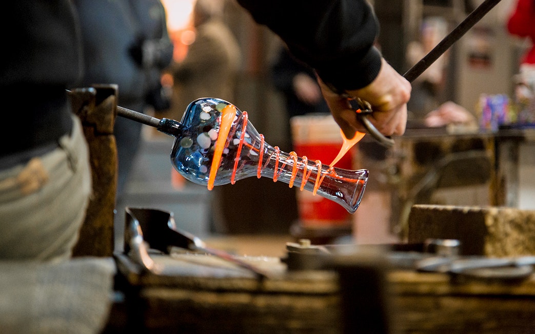 Artisan crafting glass vase in Murano workshop.