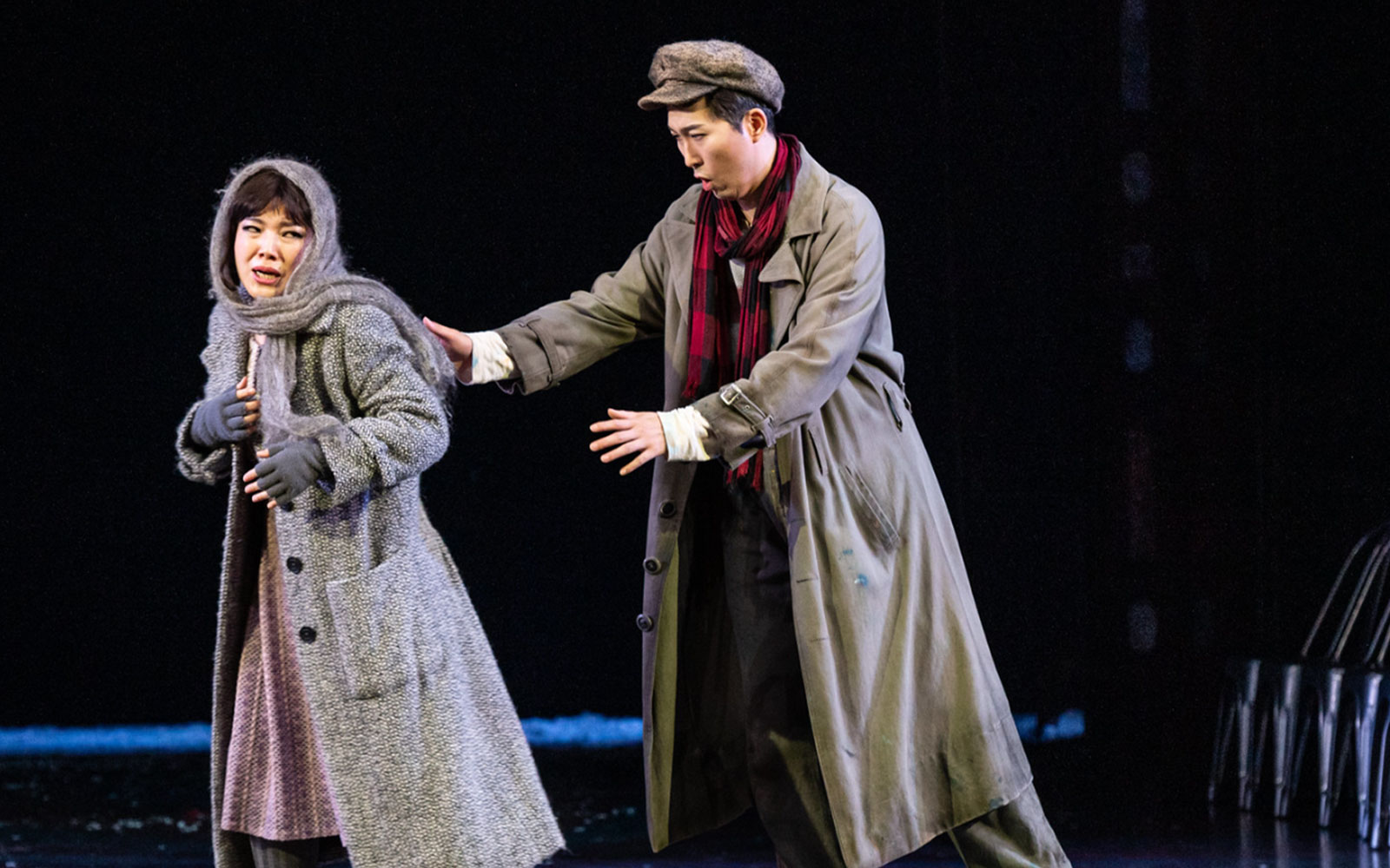 Two performers in a dramatic scene from La Bohème on stage.