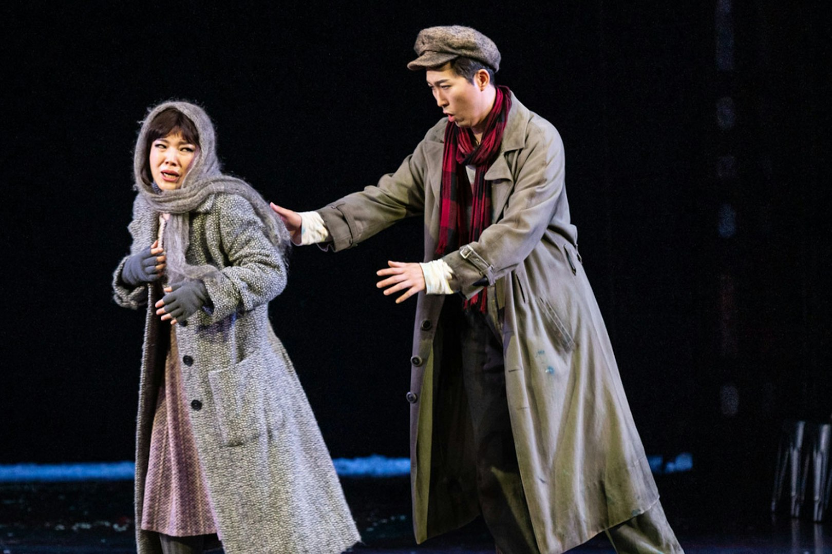 Two performers in a dramatic scene from La Bohème on stage.