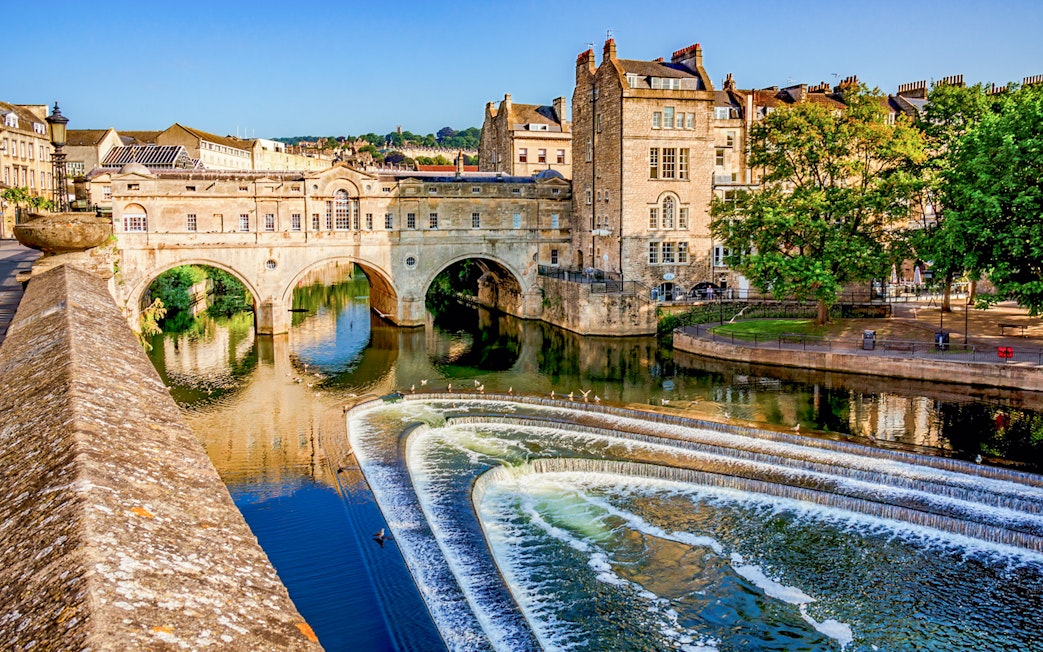 Pulteney Bridge over River Avon in Bath, England, with cascading weir in foreground.