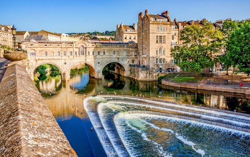 Pulteney Bridge over River Avon in Bath, England, with cascading weir in foreground.