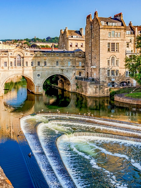 Pulteney Bridge over River Avon in Bath, England, with cascading weir in foreground.