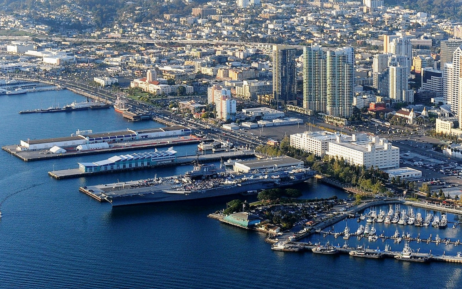 USS Midway Museum aircraft carrier docked in San Diego harbor with city skyline.