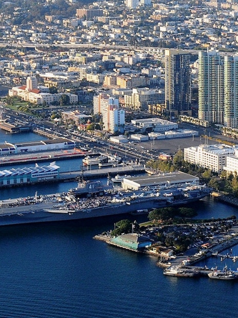 USS Midway Museum aircraft carrier docked in San Diego harbor with city skyline.