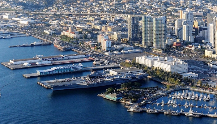USS Midway Museum aircraft carrier docked in San Diego harbor with city skyline.
