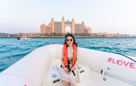 Tourist on a boat with Atlantis The Palm in the background, Dubai Marina tour.