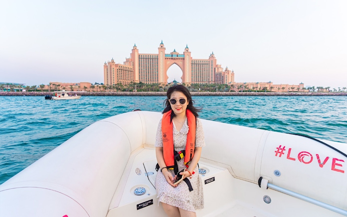 Tourist on a boat with Atlantis The Palm in the background, Dubai Marina tour.