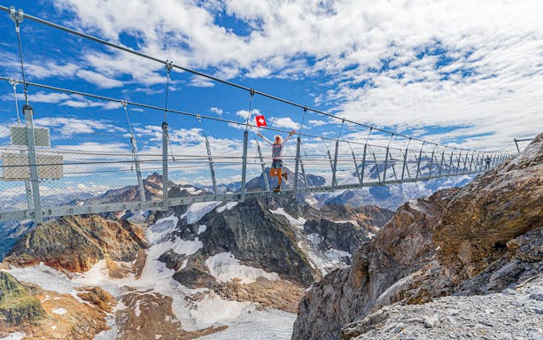 Woman walking on suspension bridge at Mt. Titlis with Swiss flag in hand.