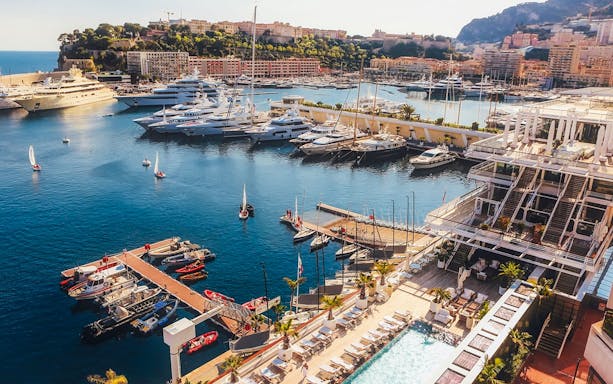 Monaco harbor with luxury yachts and waterfront view on a sunny day.