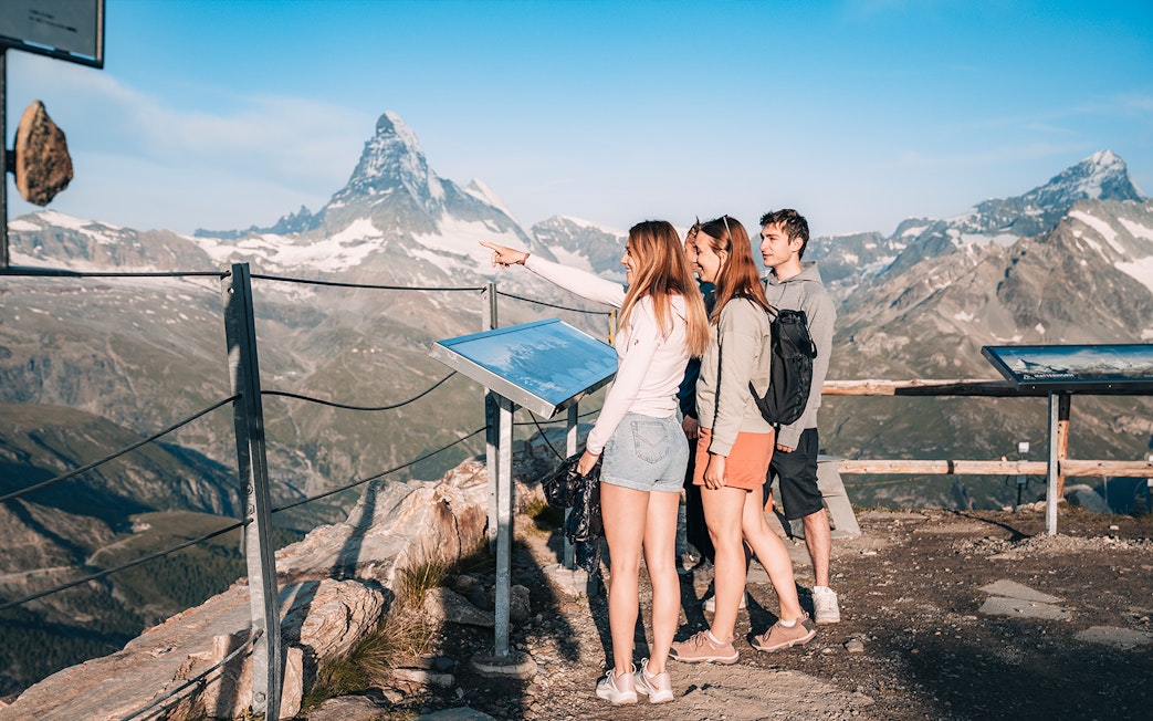 Tourists viewing Matterhorn from a glacier top with an information board in Zermatt, Switzerland.