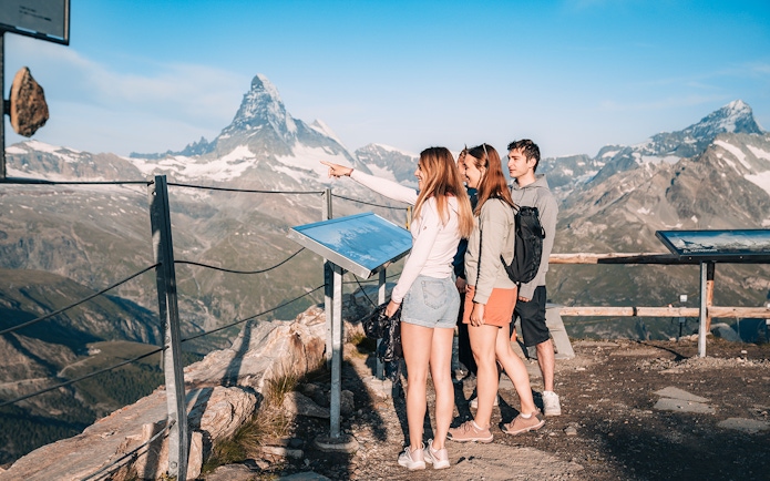 Tourists viewing Matterhorn from a glacier top with an information board in Zermatt, Switzerland.