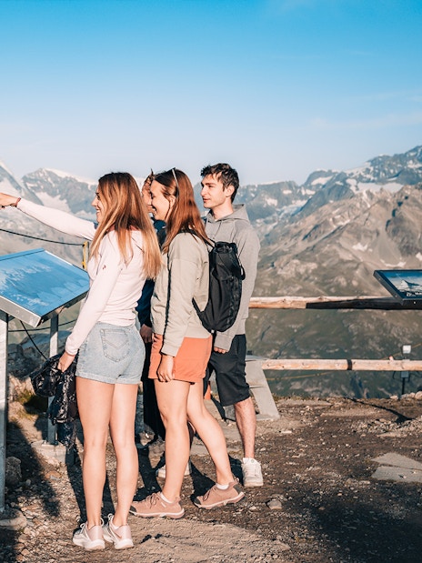 Tourists viewing Matterhorn from a glacier top with an information board in Zermatt, Switzerland.