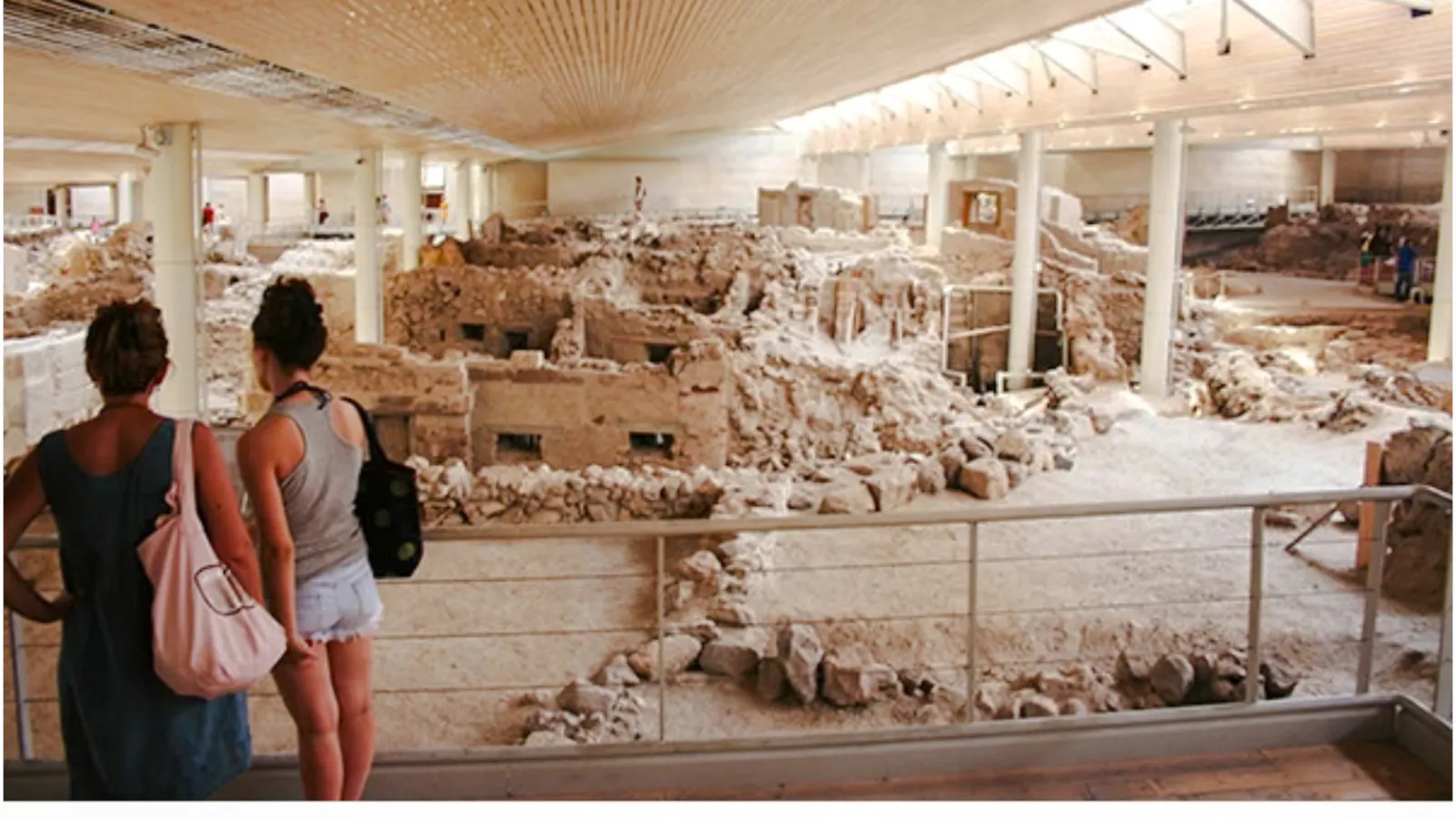 Visitors viewing Akrotiri Bronze Age ruins, Santorini archaeological site.