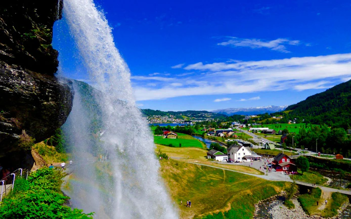 Steinsdalsfossen waterfall cascading in Norheimsund, Norway with scenic village view.