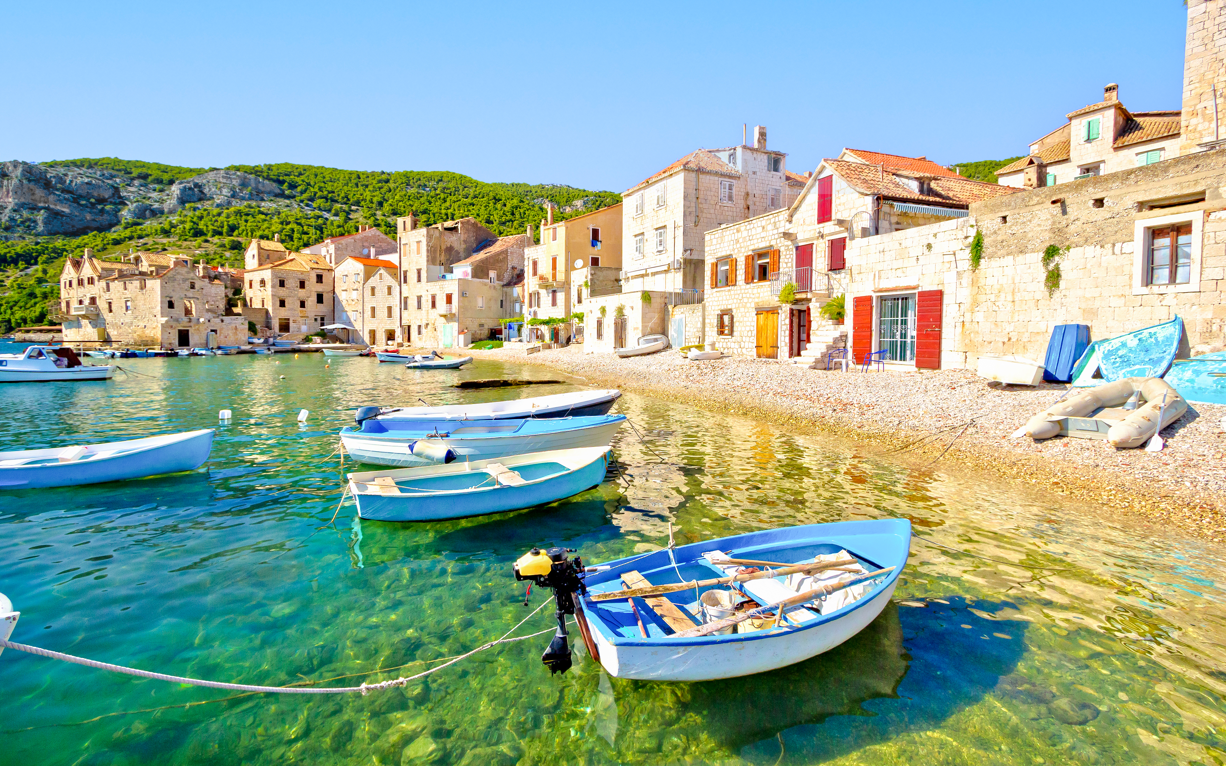 Boats anchored along the scenic beach in Komiža waterfront, Croatia.