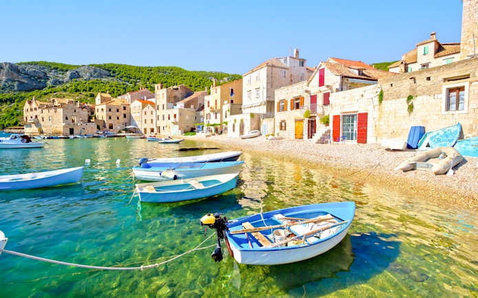 Boats anchored along the scenic beach in Komiža waterfront, Croatia.