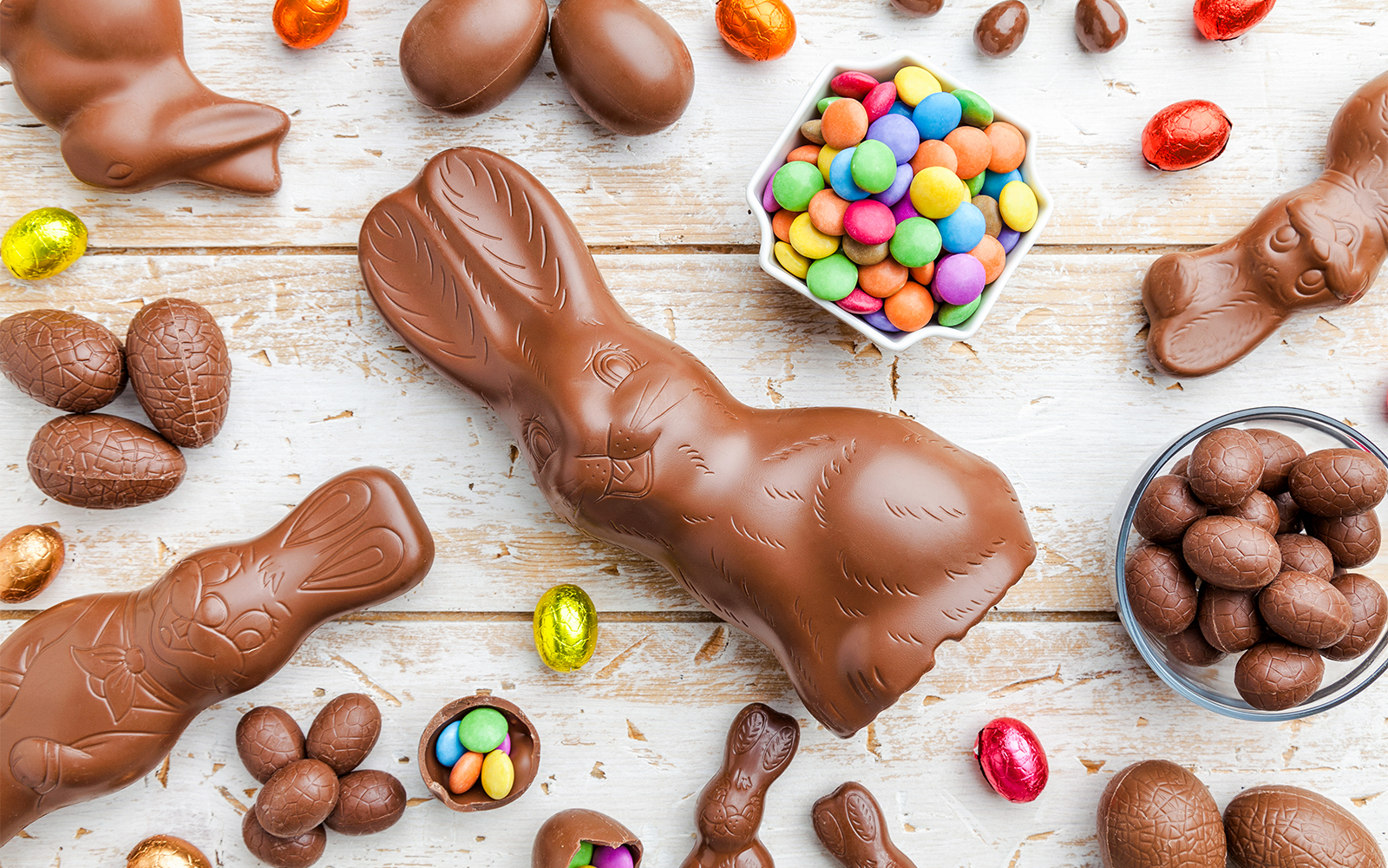 Chocolate Easter bunny and eggs on rustic wooden table.