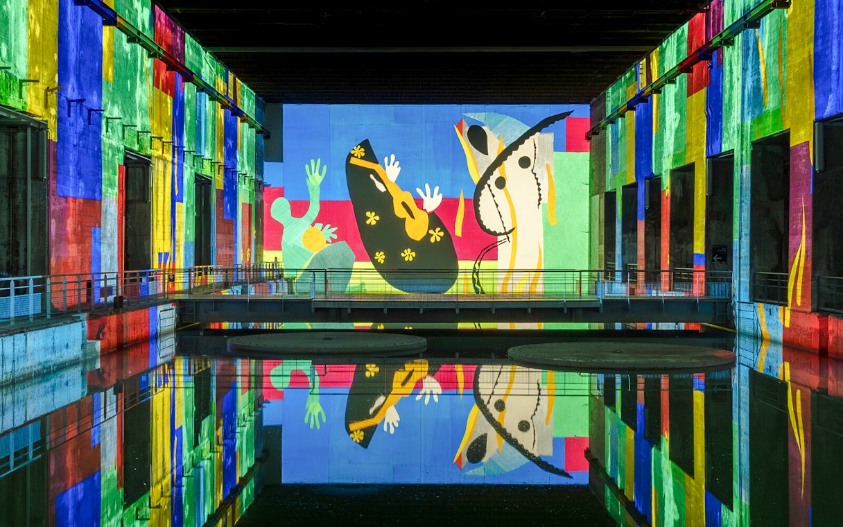 Matisse artwork projected at Bassins des Lumières exhibition, vibrant colors reflecting on water.