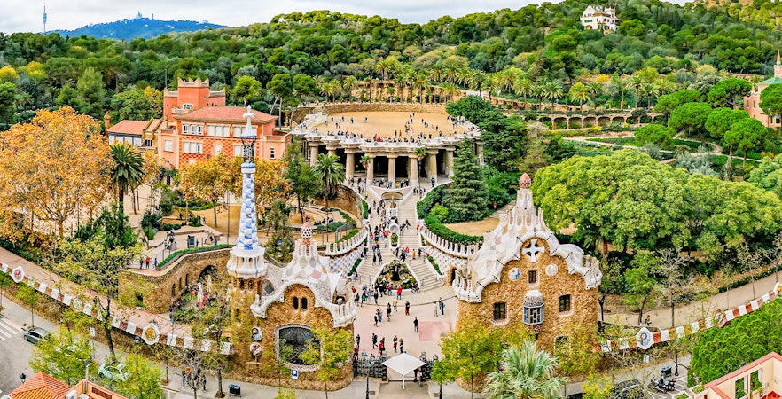 Park Guell entrance with colorful mosaic tiles and architectural details in Barcelona, Spain.