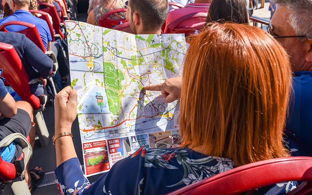 Woman examining HOHO tour bus route map in Lisbon.