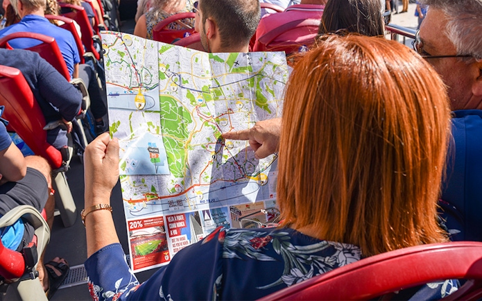 Woman examining HOHO tour bus route map in Lisbon.