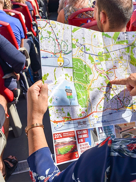 Woman examining HOHO tour bus route map in Lisbon.