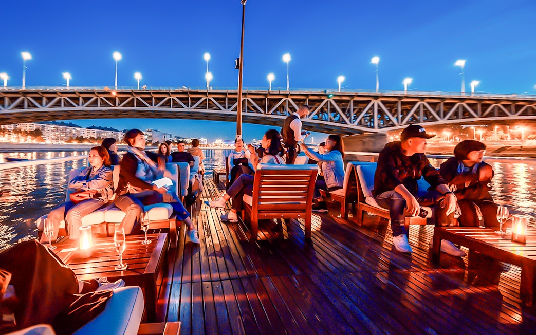 Guests relaxing on a boat during the Elegant Premium Sightseeing Cruise at night.