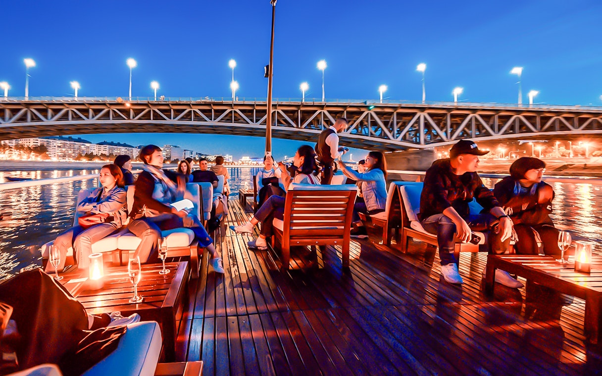 Guests relaxing on a boat during the Elegant Premium Sightseeing Cruise at night.