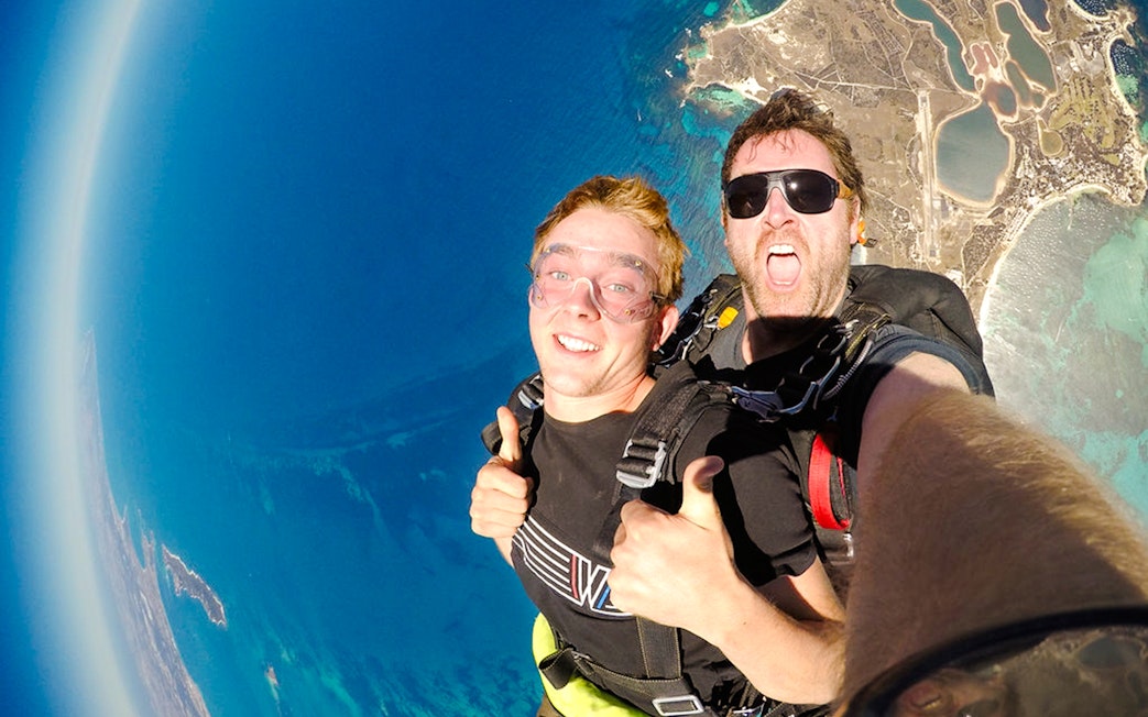 Skydivers giving thumbs up while freefalling above Rottnest Island, Australia.
