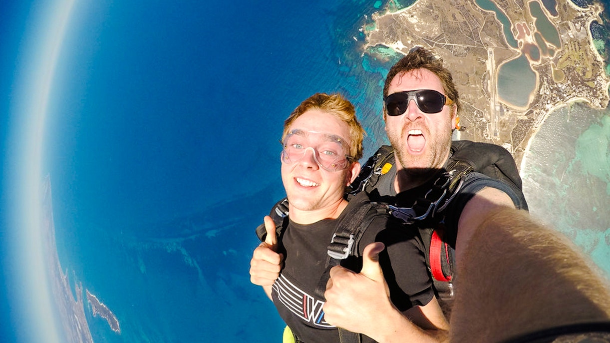 Skydivers giving thumbs up while freefalling above Rottnest Island, Australia.