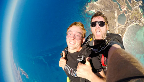 Skydivers giving thumbs up while freefalling above Rottnest Island, Australia.