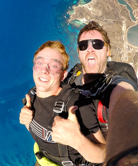 Skydivers giving thumbs up while freefalling above Rottnest Island, Australia.