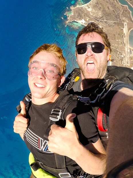 Skydivers giving thumbs up while freefalling above Rottnest Island, Australia.