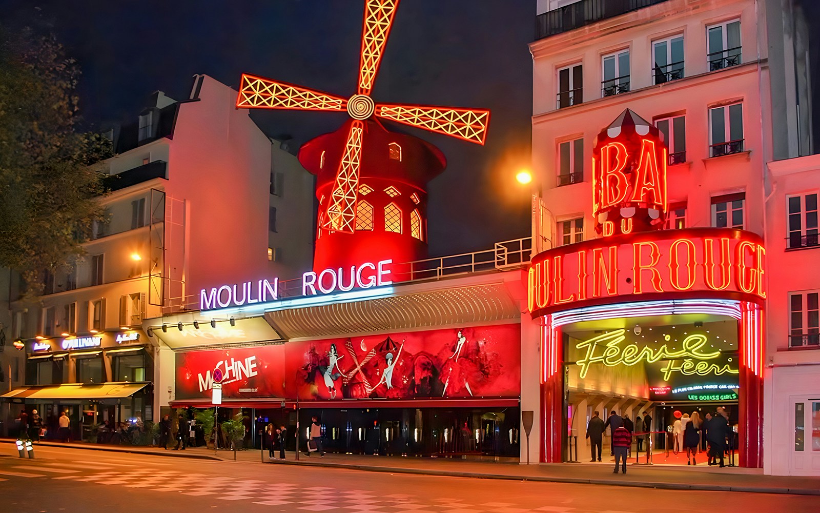 Moulin Rouge cabaret in Paris with vibrant red windmill and bustling street scene.