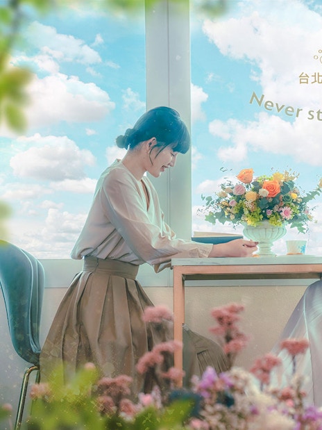 Two women enjoying a view from Taipei 101 observatory with flowers and a camera.