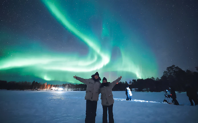 Couple enjoying Northern Lights in Levi, Finland.