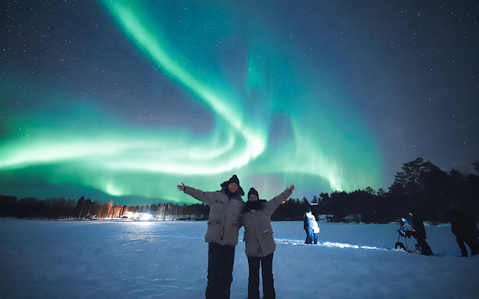 Couple enjoying Northern Lights in Levi, Finland.