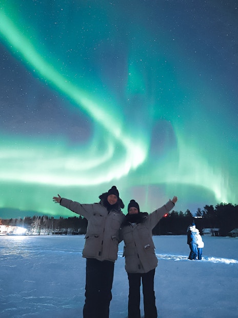 Couple enjoying Northern Lights in Levi, Finland.