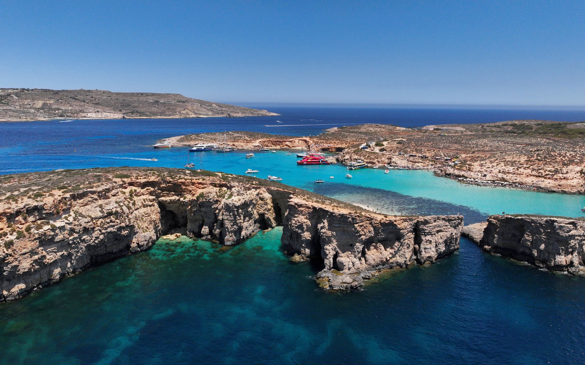 Blue Lagoon on Comino Island with boats in turquoise waters and rocky cliffs.