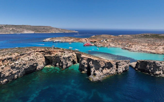 Blue Lagoon on Comino Island with boats in turquoise waters and rocky cliffs.
