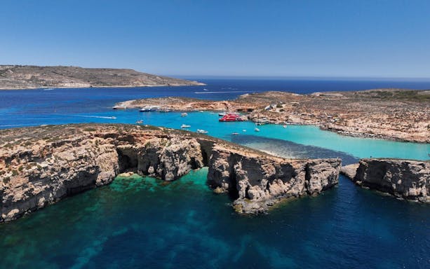Blue Lagoon on Comino Island with boats in turquoise waters and rocky cliffs.
