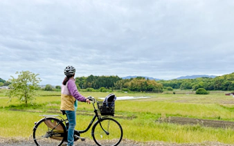 Cyclist on e-bike tour overlooking Nara countryside fields.