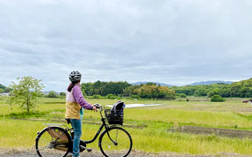 Cyclist on e-bike tour overlooking Nara countryside fields.